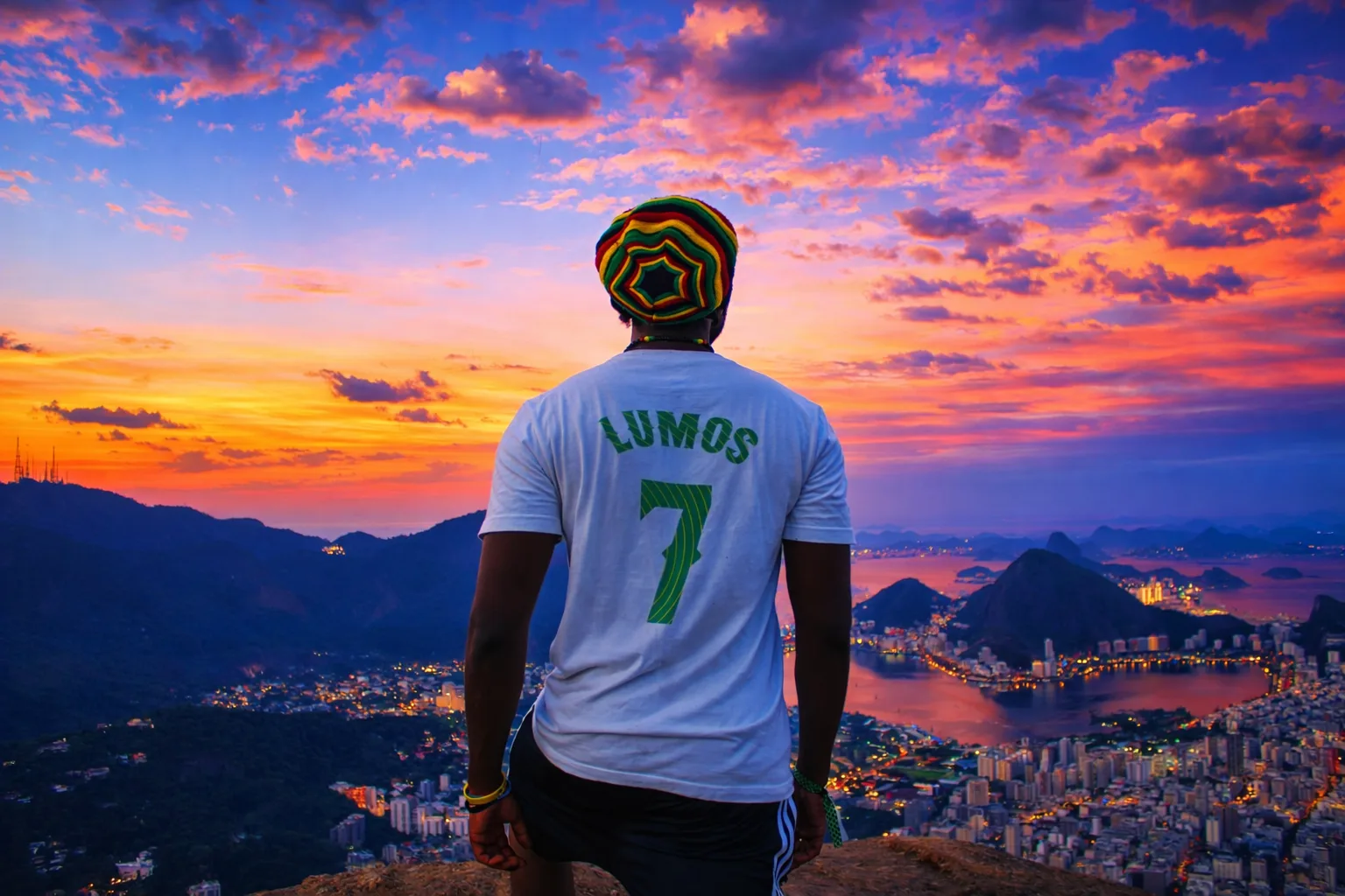 Lumos wearing a LUMOS 7 shirt overlooking a city skyline at sunset.